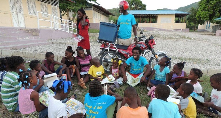 Photo d'enfants qui lisent pres d'une bibliomoto à Haiti