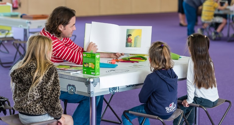 Photo de petites filles lisant un livre avec un animateur à Calais