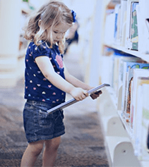 Photo d'une petite fille lisant un livre dans une bibliothèque