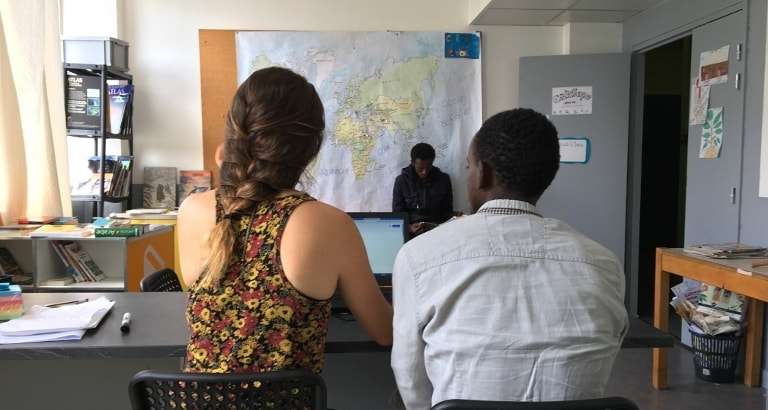 Photo d'une jeune femme et d'un migrant devant un ordinateur